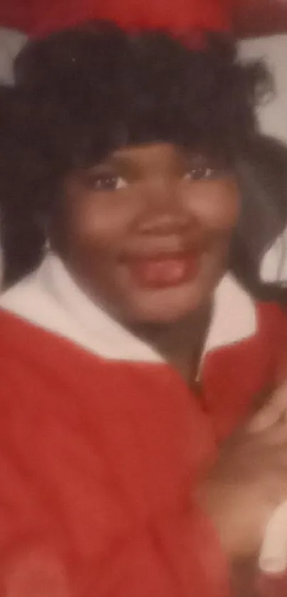 Smiling graduate in red cap and gown holding a diploma.