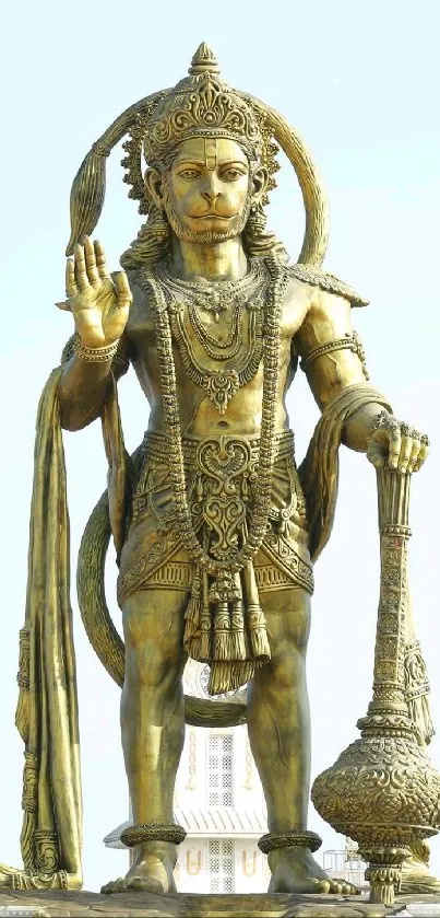 Majestic Hanuman statue with gold hue set against a clear sky background.