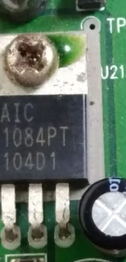 Close-up of a green circuit board with visible components like capacitors and microchips.