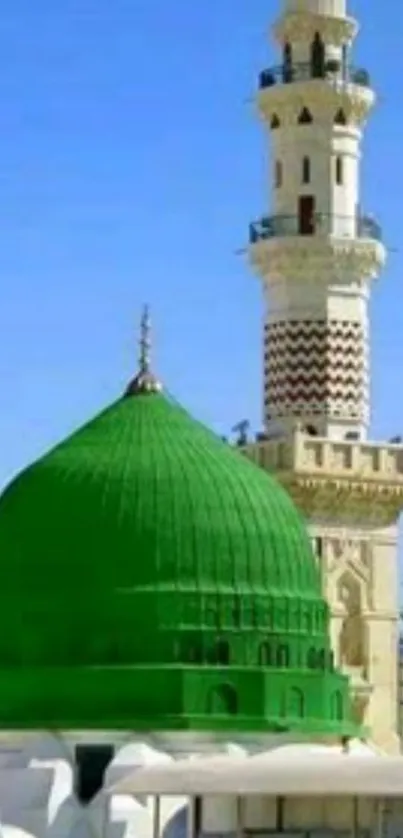 Green dome and minaret under clear blue sky background.