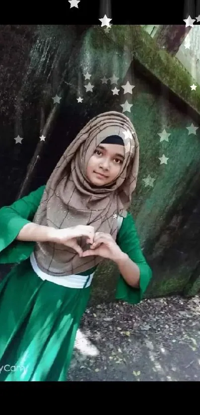 Girl in green dress making a heart gesture outdoors.