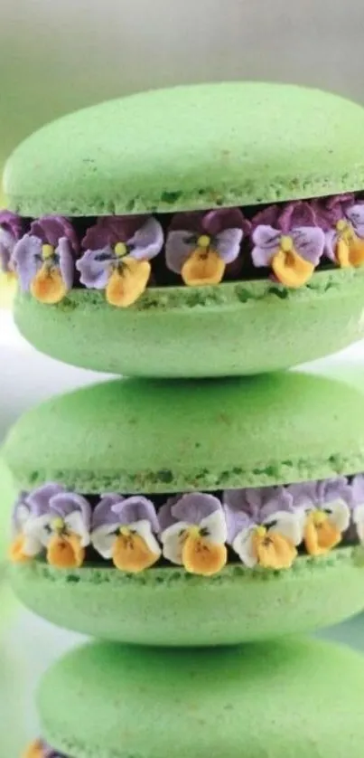 Stack of vibrant green macarons with purple and yellow floral decorations.