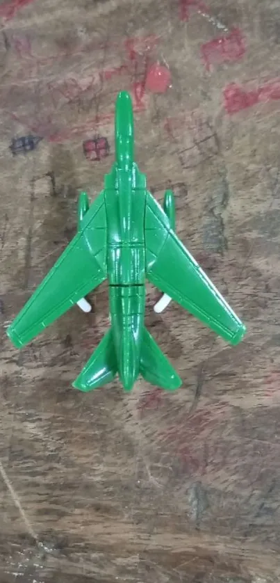 Green toy airplane on wooden textured surface.