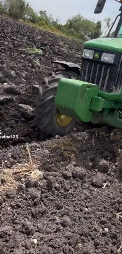 Green tractor plowing a dark, rich soil field.