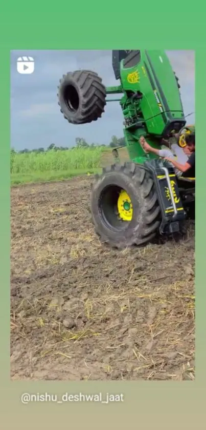 Green tractor performing a wheelie on a rural farm field.