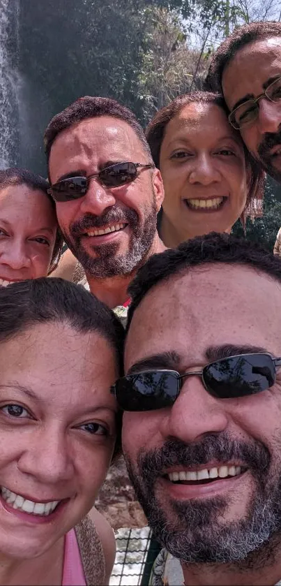 Group smiling in front of waterfall surrounded by nature.