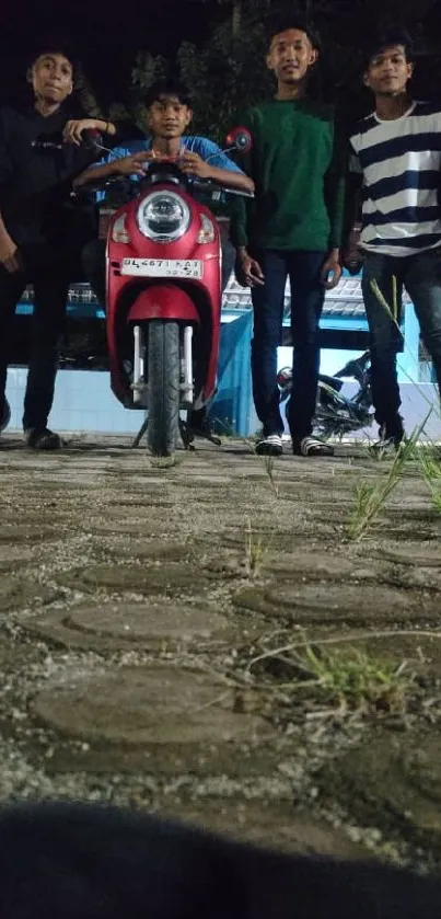 Group of people with a red scooter at night.
