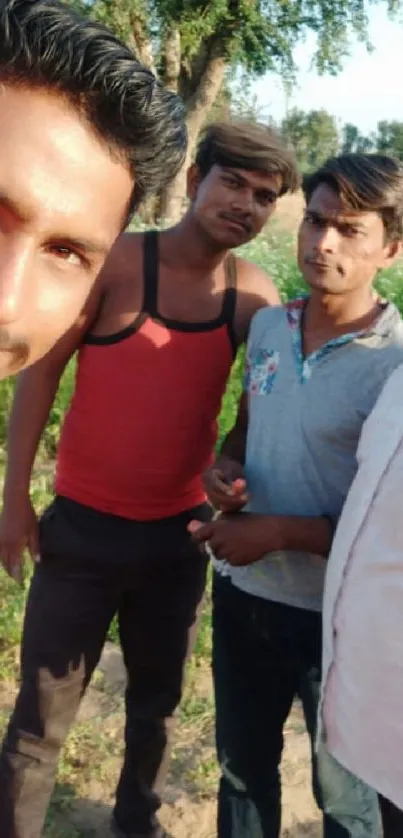 Group selfie in a sunlit outdoor field with trees.