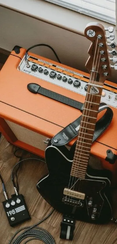 Electric guitar resting on amplifier on wooden floor.