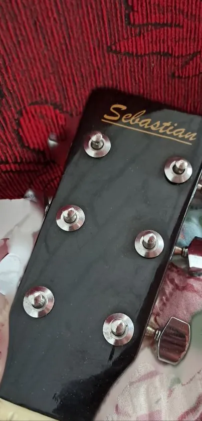 Close-up of a guitar headstock on patterned textile background.