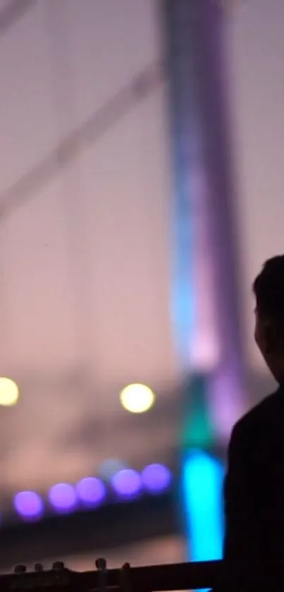 Silhouette of guitarist with purple-lit bridge at night.