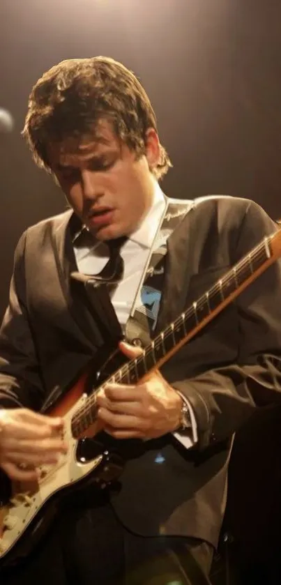 Guitarist in a suit playing on stage with intense focus.