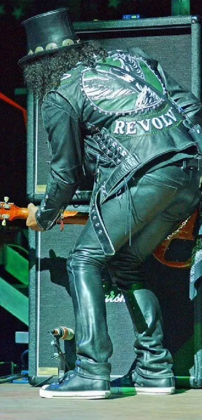 Guitarist performing on stage in leather outfit.