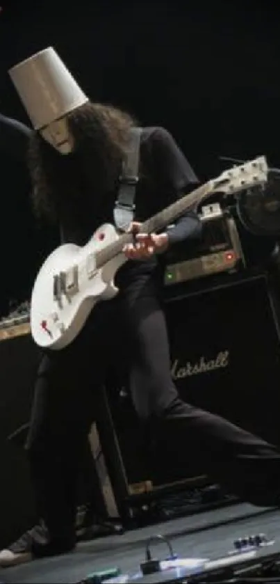 Guitarist with white guitar performing live on a dark stage.