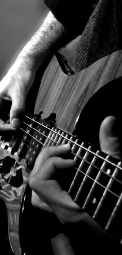 Close-up of hands playing guitar in black and white.