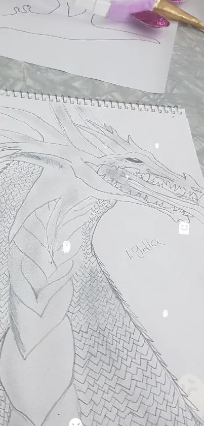 Black and white dragon sketch with intricate details on paper.