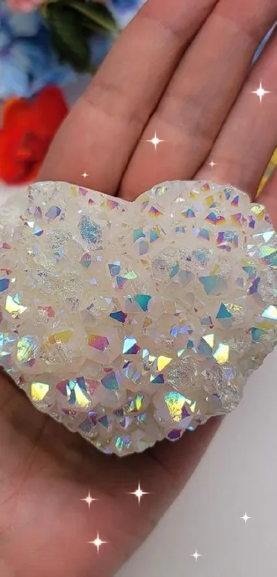 Hand holding a sparkling, iridescent heart stone with a floral background.