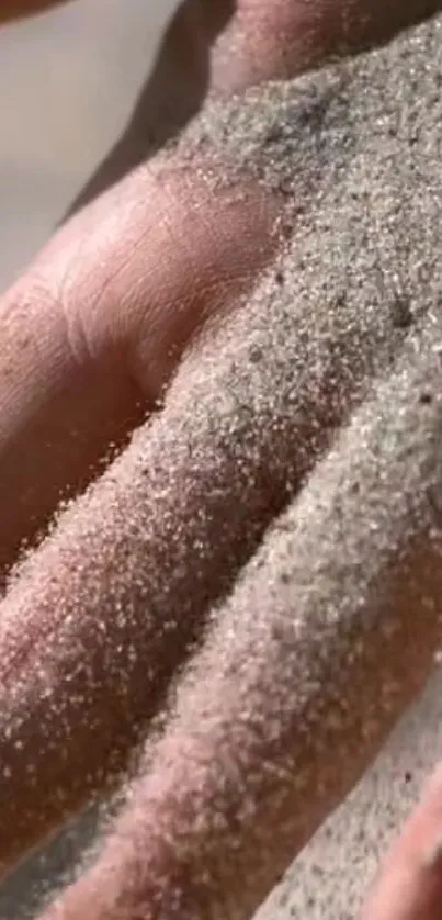 Close-up of a hand covered with sand, showing texture.