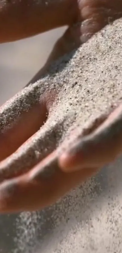 A hand gracefully letting sand flow through fingers.