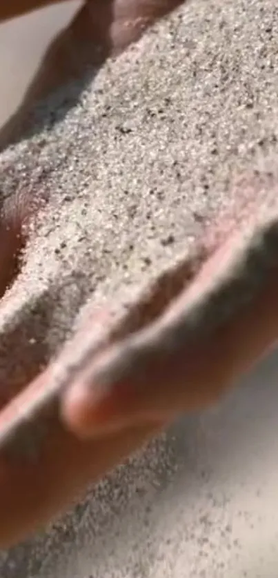 A close-up of a hand gently sifting through fine sand.