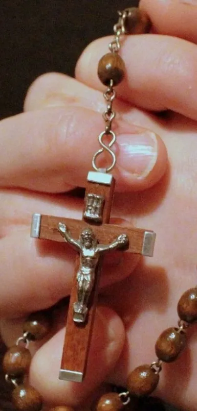 Hands holding a cross-styled rosary in prayer.