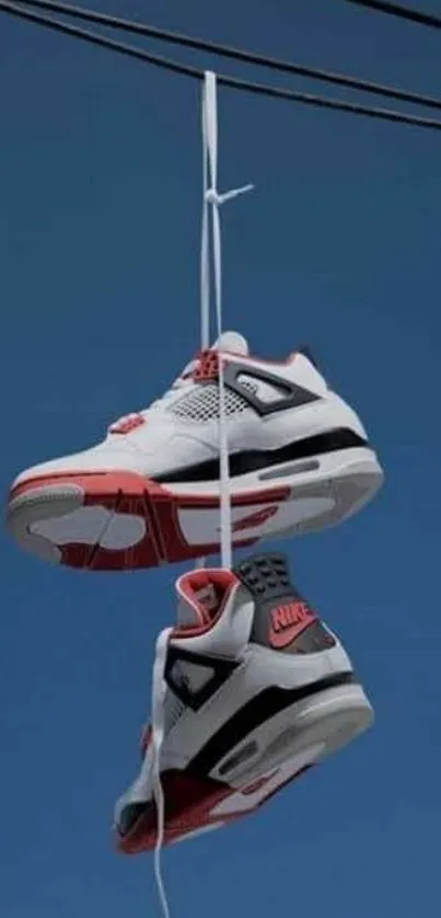 Sneakers hang from a wire against a blue sky.