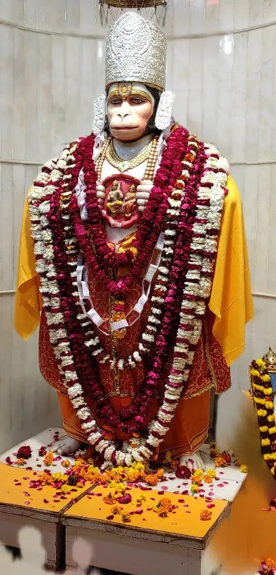 Hanuman statue adorned with garlands in a temple setting.