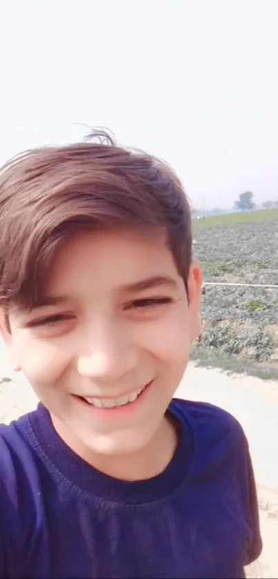 Smiling boy outdoors with rural background.