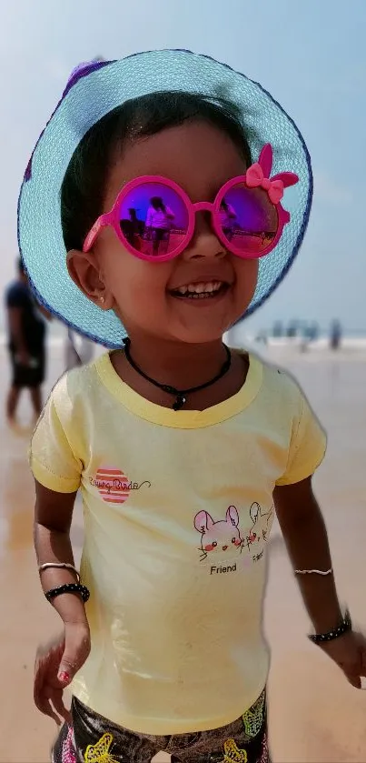 Smiling child in pink sunglasses on a sunny beach.