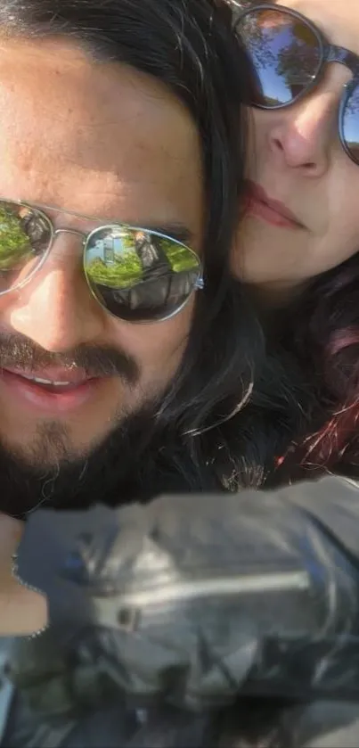 Smiling couple wearing sunglasses outdoors.