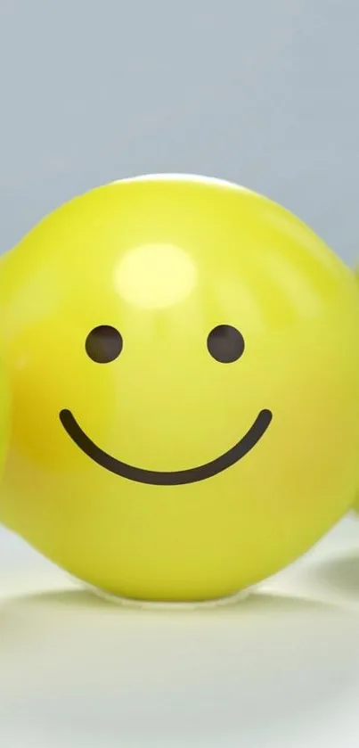 Yellow smiley face balloon with a cheerful expression on a light background.