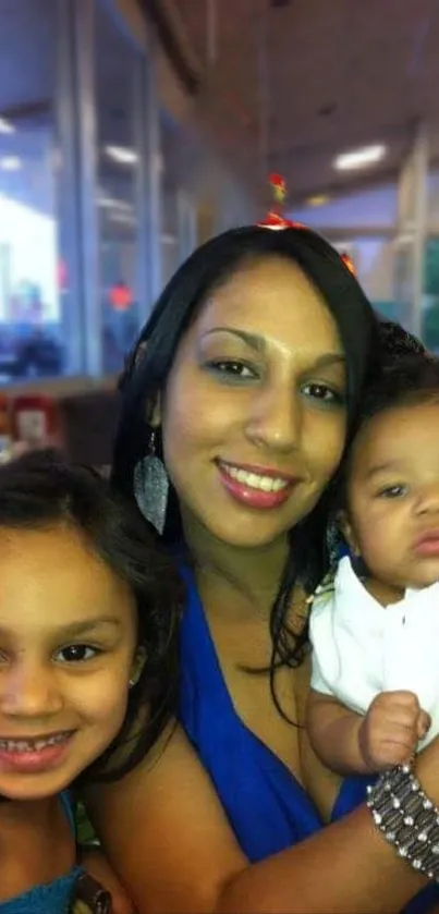 Woman holds smiling children indoors. Cozy family scene.