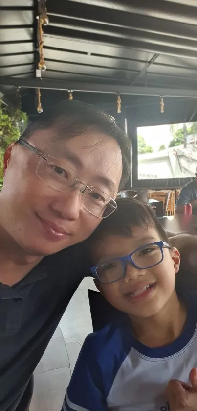 Father and son smiling together in a cafe setting.