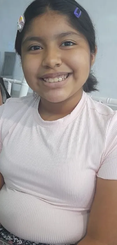 Young girl smiling in a pink shirt, close-up portrait.