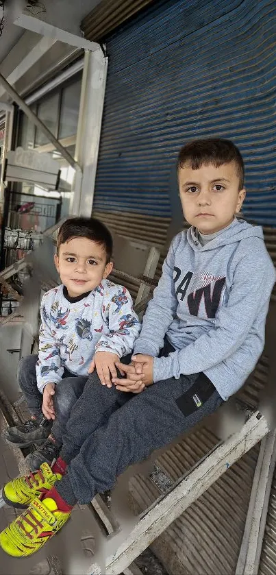 Two kids sitting in an urban setting, showcasing playful energy.