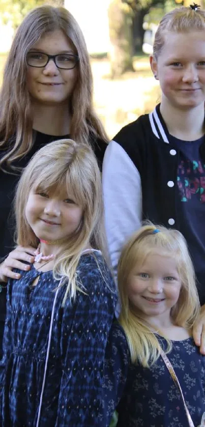 Outdoor photo of four smiling girls with a green nature background.