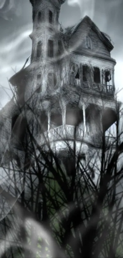 Haunted house with fog and bare trees in eerie mobile wallpaper.