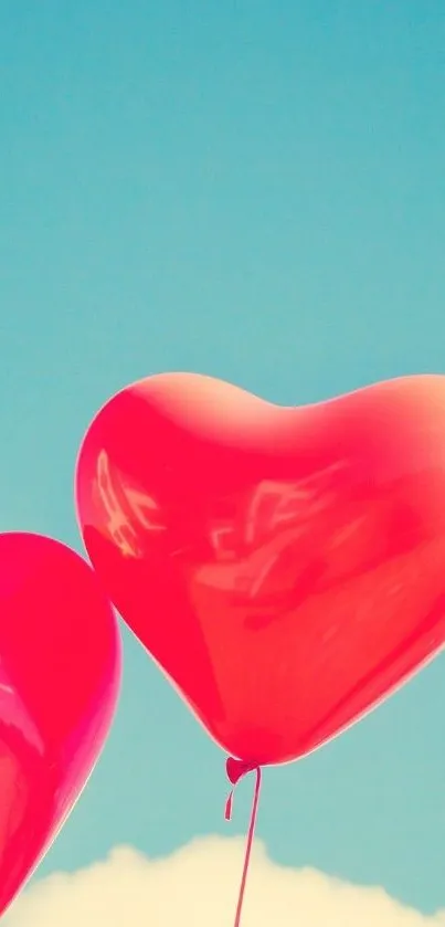 Red heart balloons float in clear blue sky.