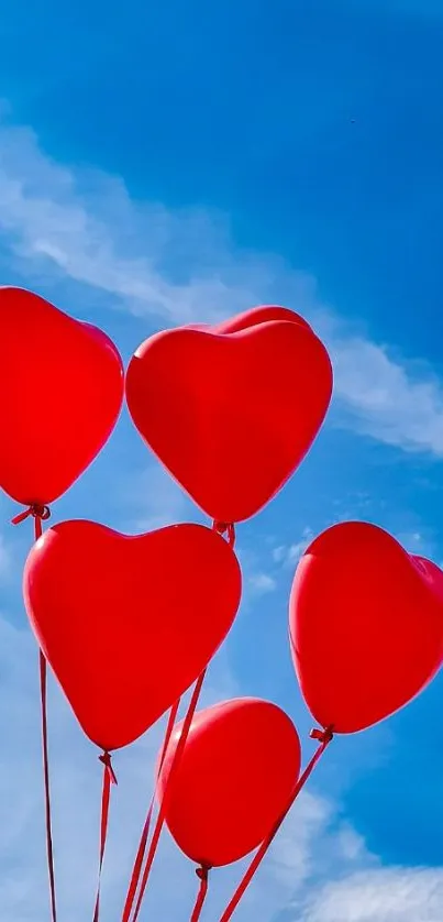 Heart-shaped red balloons float in a blue sky.