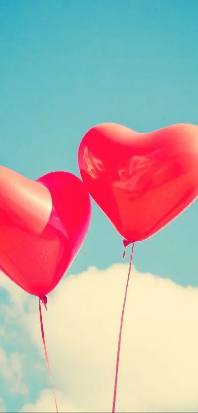 Two red heart-shaped balloons float in a sunny blue sky.