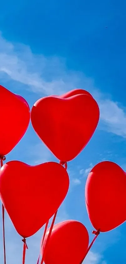 Heart-shaped red balloons against a bright blue sky.