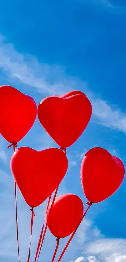 Heart-shaped red balloons floating in a bright blue sky wallpaper.