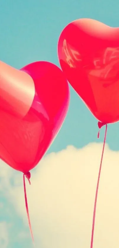 Red heart balloons floating in a blue sky.