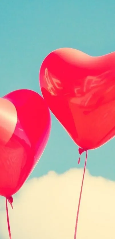 Two heart balloons floating in a bright blue sky.