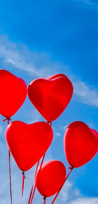 Red heart balloons floating against a bright blue sky wallpaper.