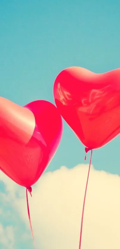 Two red heart-shaped balloons against a blue sky with clouds.