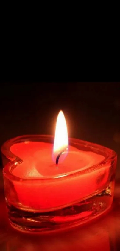 Heart-shaped red candle glowing warmly in the dark, creating a romantic ambiance.