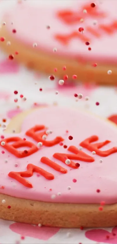 Heart-shaped pink cookie with 'Be Mine' written on top, surrounded by sprinkles.