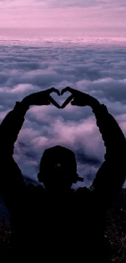 Silhouette making a heart against purple sunset.