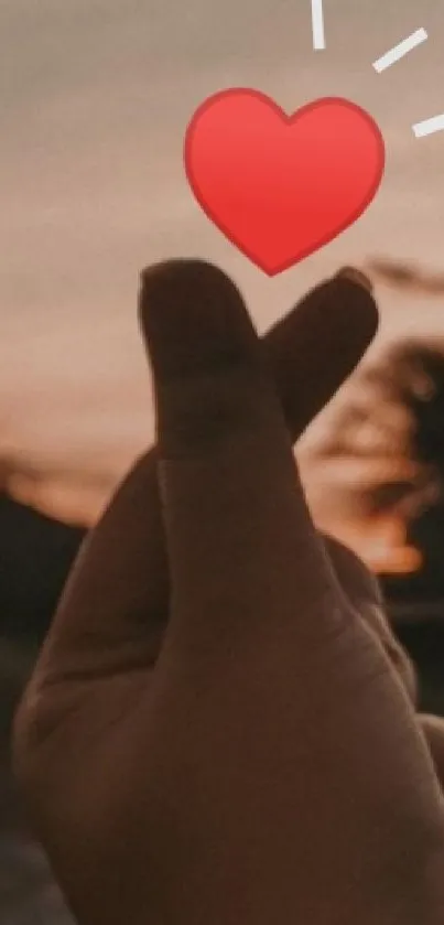 Hand making a heart gesture against a sunset sky.